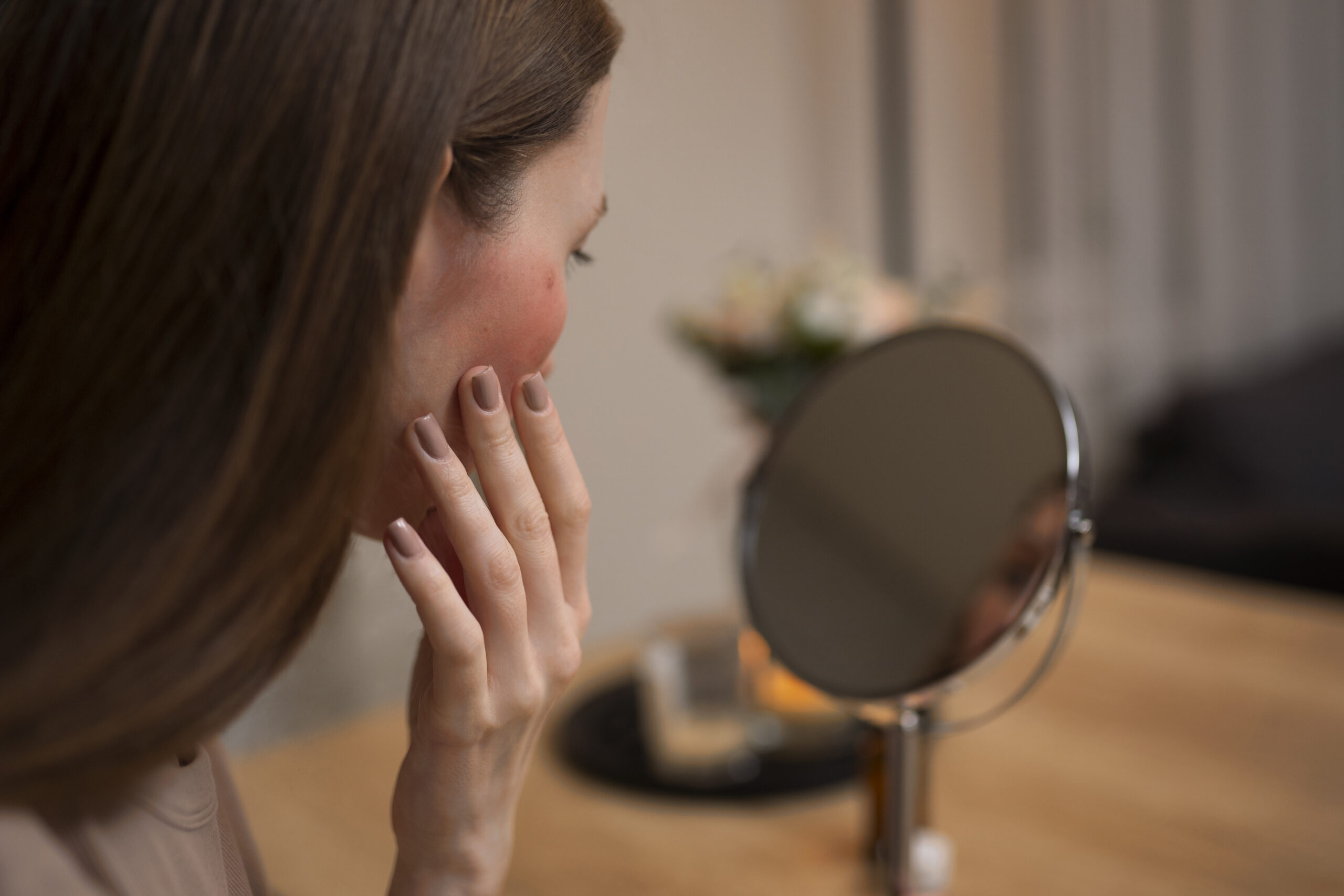 woman looking her rosacea mirror scaled